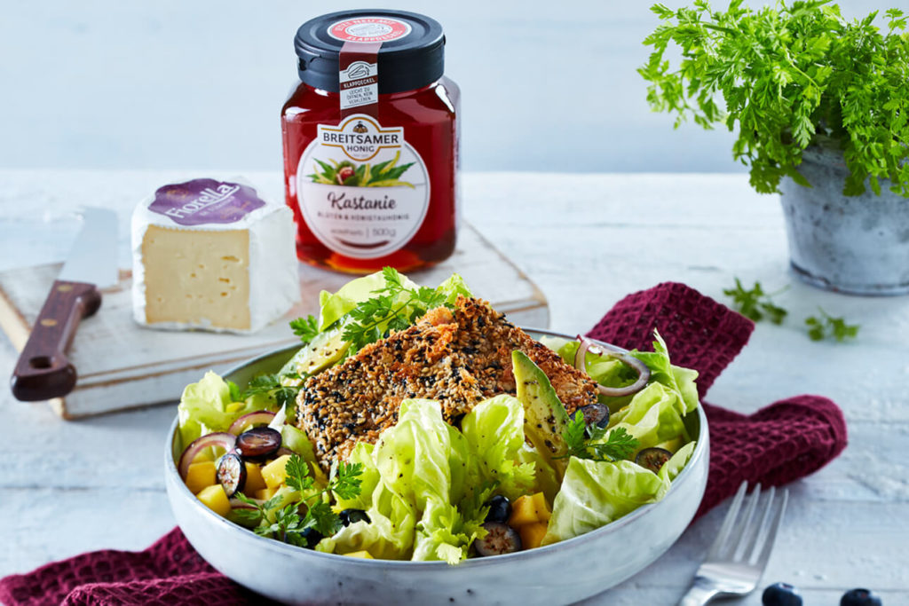 Summer salad with cheese and chestnut honey on a white wooden table