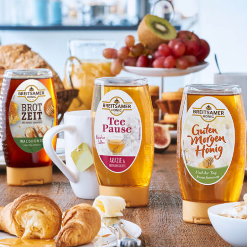 Drei Breitsamer Dosierspende integriert in eine Frühstücksszene auf einem gedeckten Tisch mit Obst, Croissants und Orangensaft