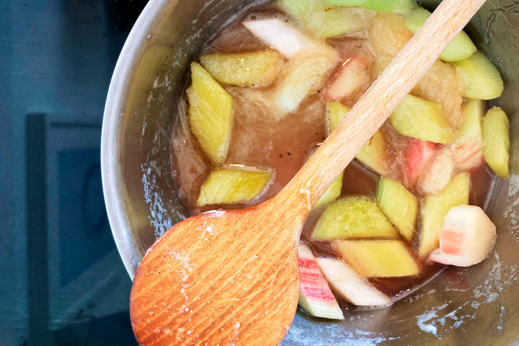 Rhabarberkompott köchelt in Kochtopf mit Holzlöffel