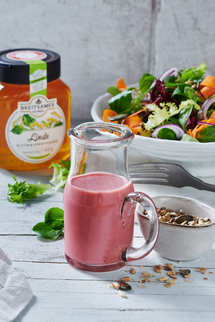 Breitsamer Honig-Senf-Dressing auf weißem Tisch mit buntem Salat