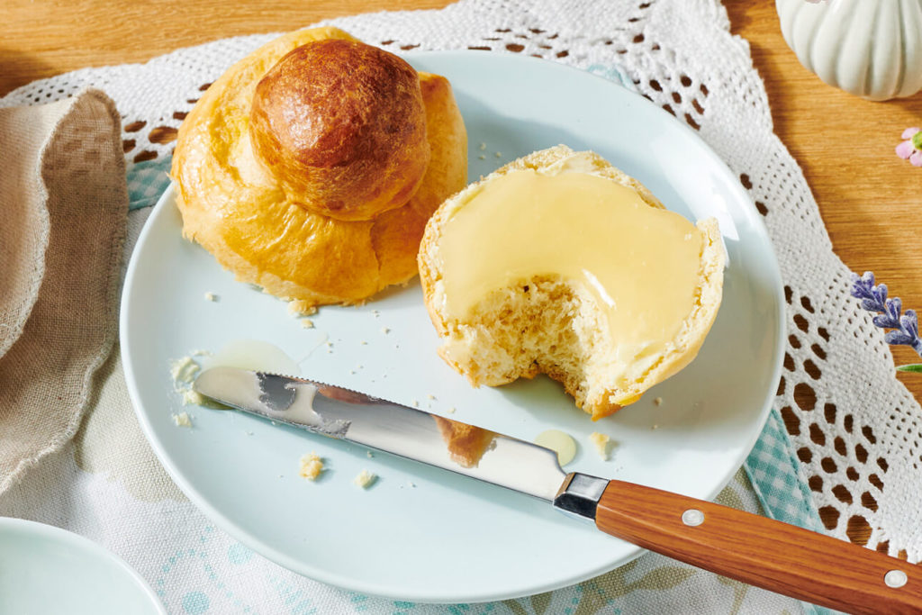 Teller mit aufgeschnittenem Brioche, eine Hälfe bestrichen mit Honig